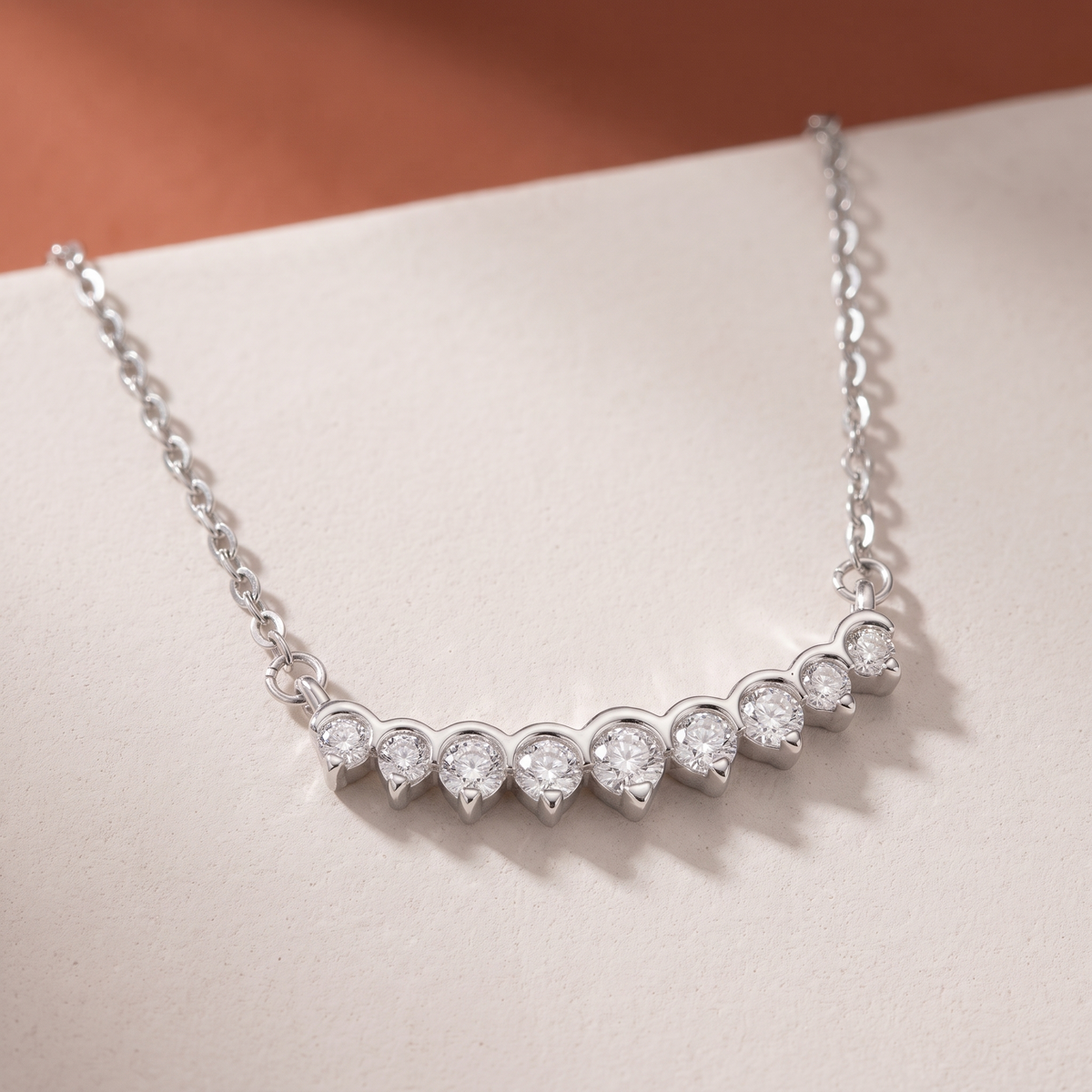 Moissanite curved bar necklace on a plaster slab against terracotta