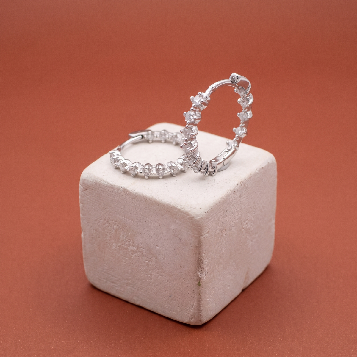 Inside-out moissanite hoops on a plaster cube against terracotta