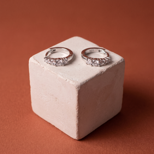 Five-stone moissanite huggies on a plaster cube against terracotta